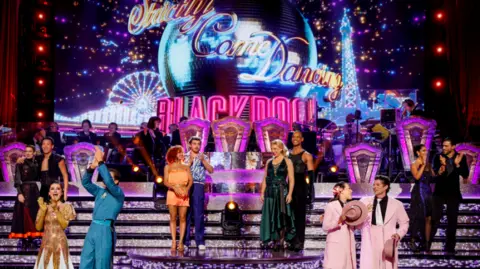 Still from Strictly Come Dancing Blackpool event with multiple couples on a brightly decorated stage.