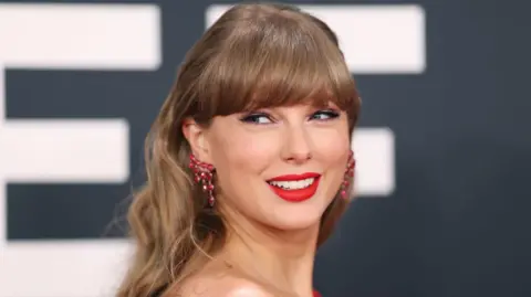 Getty Images Taylor Swift looks over her shoulder and smiles on the red carpet at the Grammy Awards earlier this year
