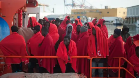 Getty Images Migrants are seen standing on a rescue boat as they wait to disembark after their arrival at the Port of Malaga, Spain