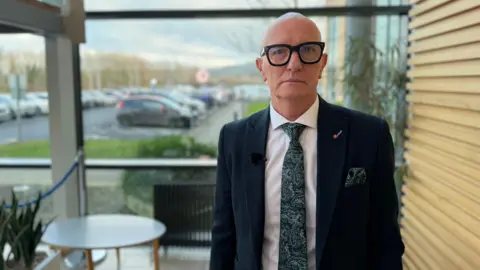 A bald man with black rimmed glasses and 