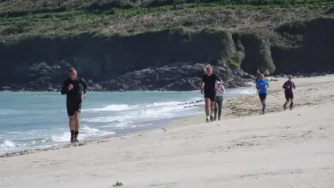 People run along a beach