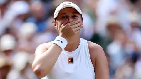 Amanda Anisimova covers her mouth with her hand