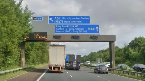 Google Google streetview of lorries and cars driving on the M60 with blue motorway signs overhead for the junction 24 exit to Denton