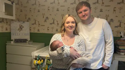 Abbie Foord Abbie Foord and her partner holding their new-born baby.