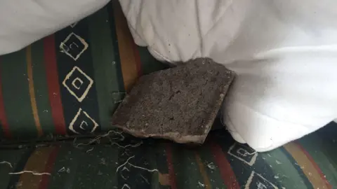 A concrete slab on a green bed. There are also shards of broken glass on the bed.