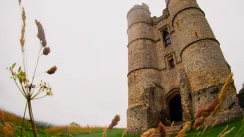 Two stone towers sit either side of an archway. They are imposing and stand in a grey sky.