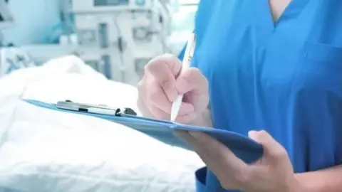 BBC A nurse writing on a clipboard