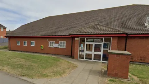 Google Parkside Community Centre is a one-storey brown brick building with glass doors. There is a small grassed area in front of it. 