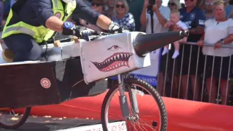 Rachel Wield A close up of an angry shark face on the side of a metal pointy bike.