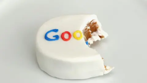 Getty Images A small hand-sized cake with a bite taken out of it - and the Google logo in icing on top - is seen in this photo