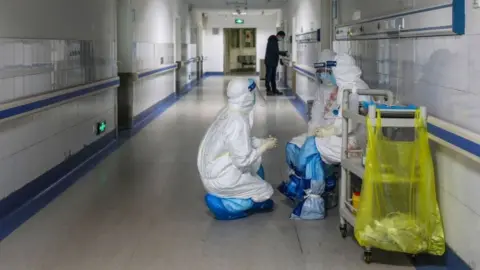 Getty Images This photo taken on February 16, 2020 shows medical staff members talking at the Wuhan Red Cross Hospital