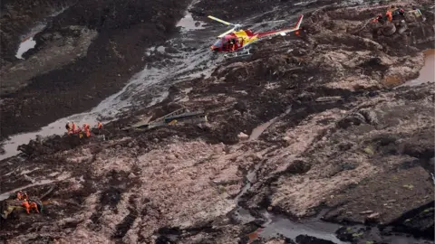 AFP/Getty Images Rescuers search for missing people after the collapse of the dam in Brazil