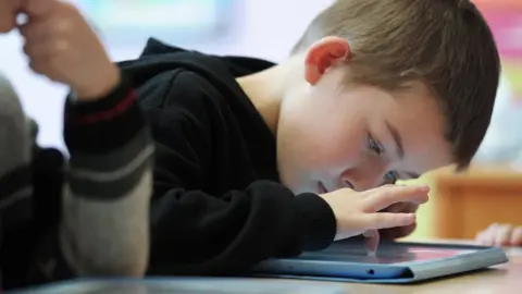 Getty Images A boy looks at a tablet