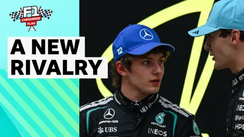 Andrea Kimi Antonelli and George Russell look towards each other wearing Mercedes race suits