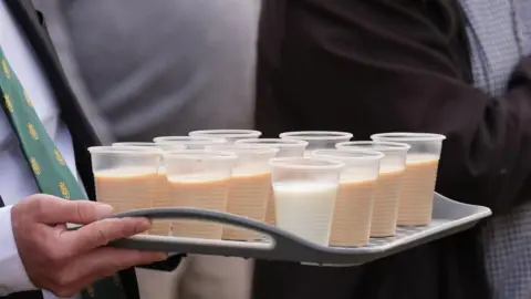 PA Media A close-up of a tray with cups of milk and rum.