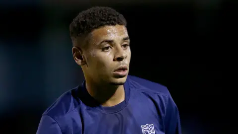 PA Media Chiedozie mengenakan kemeja United Southend biru. 