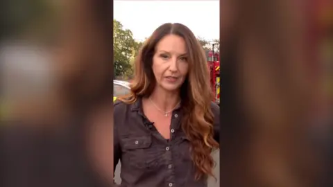 Woman with long brown hair standing in front of fire truck