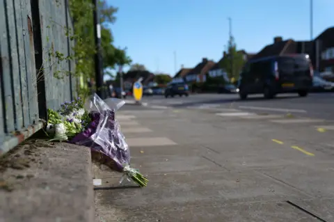 PA Media White and purple flowers in a bouquet at roadside. Vehicles are in the background