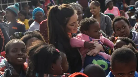 Sun International PR agency Miss South Africa holding a black child with no gloves