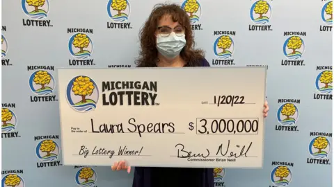 Michigan Lottery Laura Spears holding a giant cheque