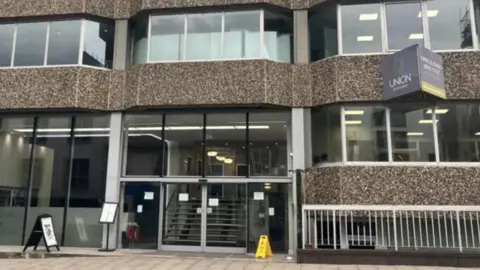 Front aspect of office building depicting windows, stairs and pavement