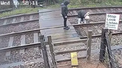 Two young people "lingering" on a path over a rail crossing