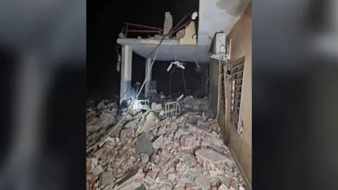 WHO A white hospital bed seen amongst the rubble at night at el-Daein Teaching Hospital