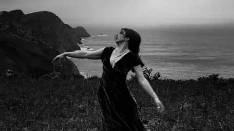 A woman dancing on a Welsh coastal path