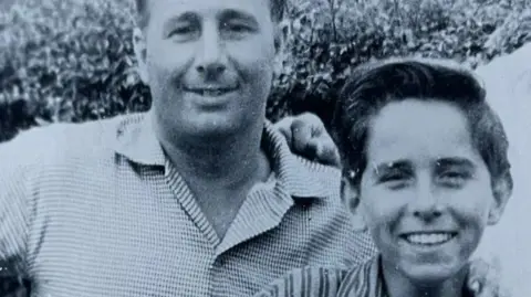 Family photograph Black and white photograph of a man and a young boy, smiling at the camera.