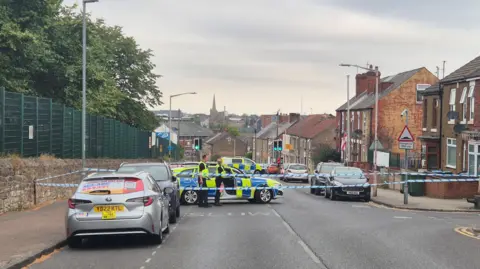 Police car with a cordon on a road with a downhill slope
