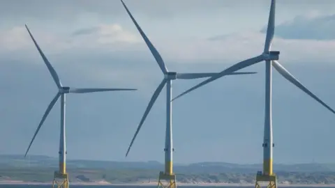 Three offshore wind turbines in the sea off the coast of the UK