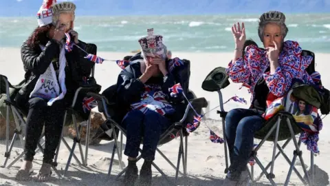 Reuters People hold up masks depicting Britain's Queen Elizabeth