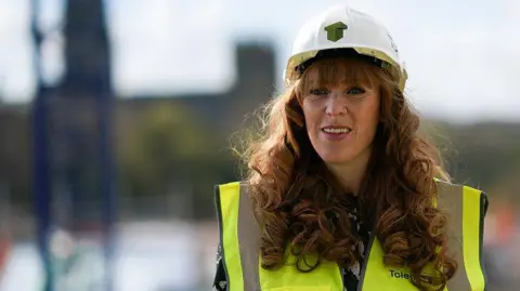 Getty Images Wearing a white hard hat and a hi vis jacket Labour's Angela Rayner visits a building development project on the banks of the River Wear in Durham