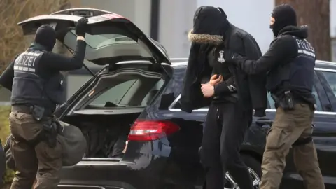 Reuters One of twelve men escorted by police