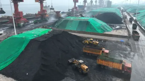 Getty Images Coal is loaded onto trucks for delivery to power generation plants, after being unloaded from ships at the port in Lianyungang, in China's eastern Jiangsu province on July 12, 2023