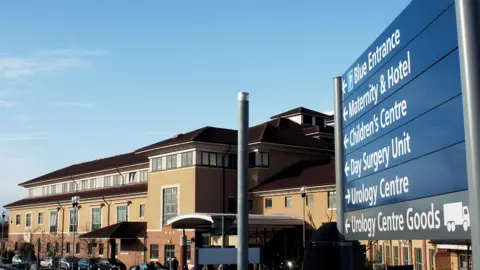 PA Media A photo of City Hospital in Nottingham with a blue sign on the right of the frame showing directions for the 'Blue Entrance, Maternity and Hotel, Children's Centre, Day Surgery Unit, Urology Centre and Urology Centre Goods. 