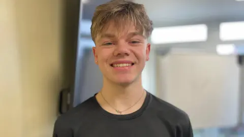 Johan has sandy blond hair and is smiling, wearing a black t-shirt.