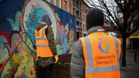 Getty Images Young offenders do manual work erecting a flower display box as part of a Community Payback Scheme