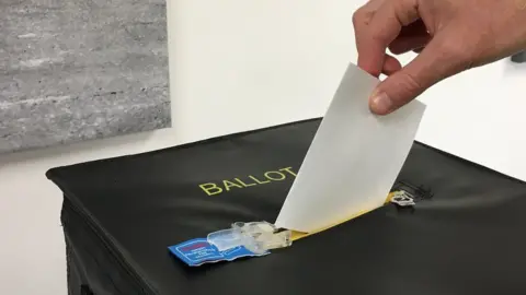 BBC Someone places their vote in a ballot box during Guernsey's 2018 referendum