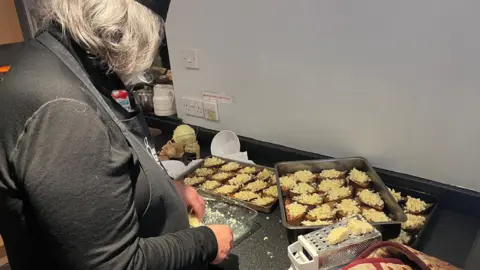 A chef is putting cheese on top of sourdough bread on a kitchen counter. 