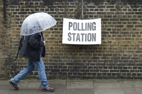 Getty Images Man with umbrella outside polling station