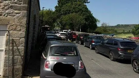 Gill Stockdale A large number of cars parked on a small lane in a village in the Yorkshire Dales