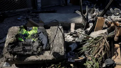 Reuters A burnt high-vis overgarment connected apical of a fallen actual artifact beside a heap of rubble.