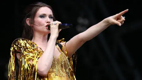 EPA Sophie Ellis-Bextor on stage in a sparkly gold top, holding a microphone.