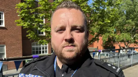 BBC A policeman in uniform stood outside