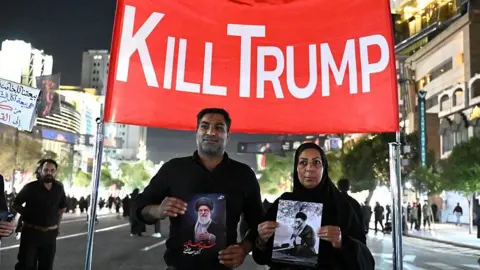 Getty Images Mourners display an anti-US banner as they arrive near Imam Reza's shrine for the funeral of slain Iranian leader Ali Khamenei and members of his family in Mashhad early on July 9, 2026.