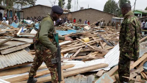 Reuters Police officers stand on the debris of a collapsed school classroom