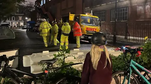 Sarah Gibbons Girl looks on at contractors walking away