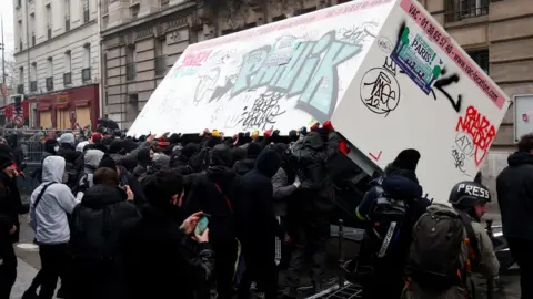 AFP Demonstrators overturn a container during a demonstration against the pension overhauls, in Paris, on 5 December, 2019.