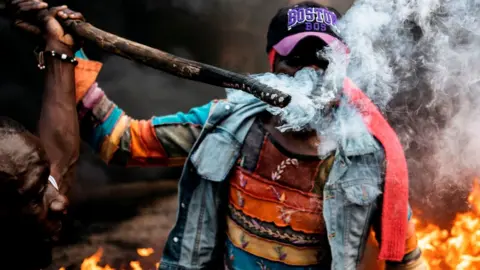AFP A man holds a burning stick as opposition supporters demonstrate at a burning barricade in Kibera, Nairobi, 25/10/2017